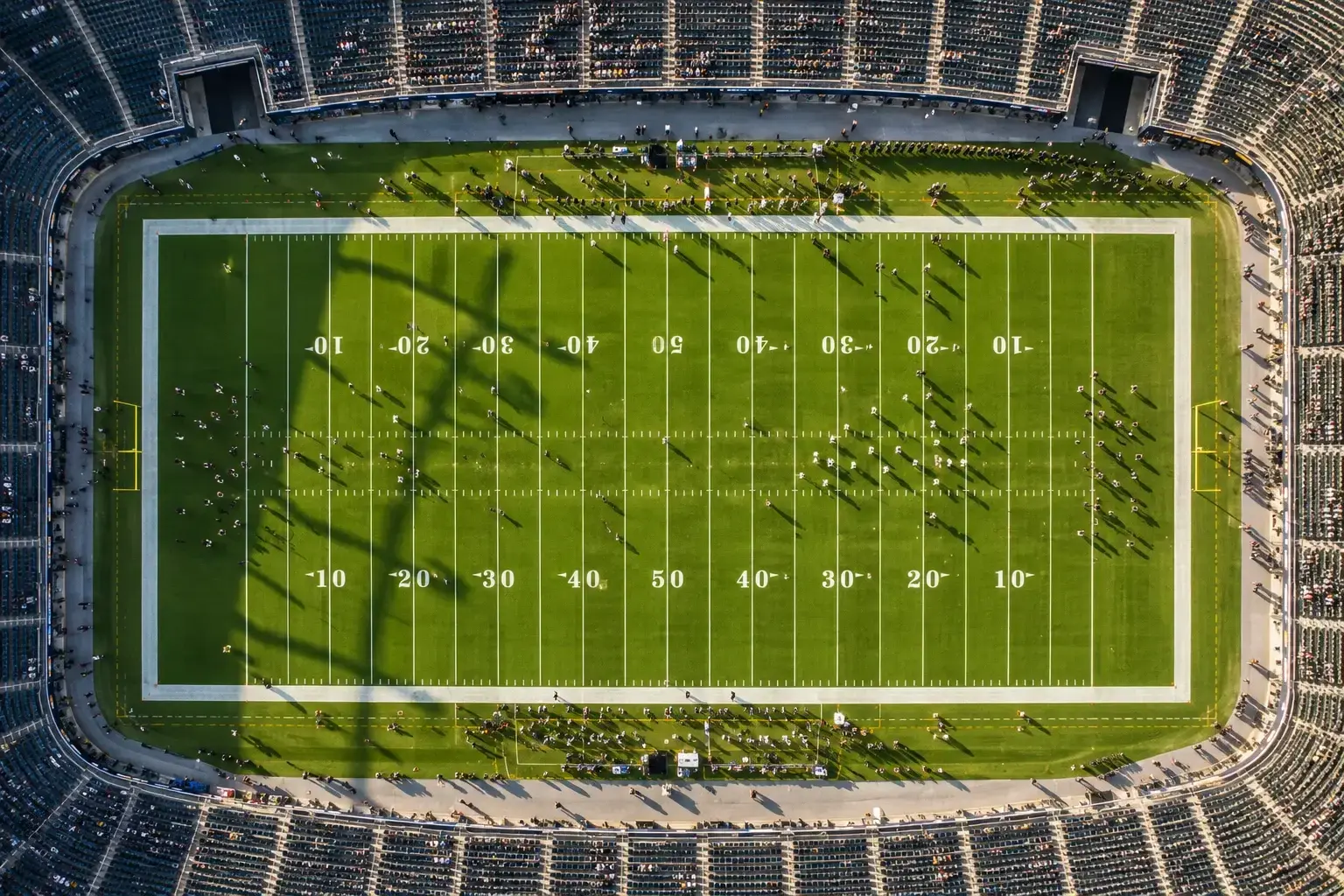 NFL football field viewed from above on gameday with yard line markings and team formations visible